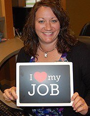 Team member smiling with I love my job sign