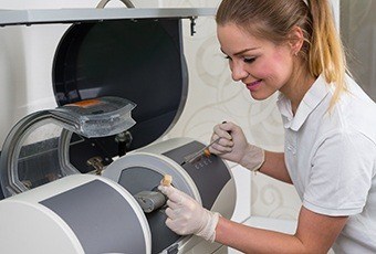 Female dental employee using CEREC milling unit