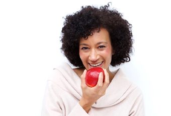 woman with dental implants in Ripon biting into red apple