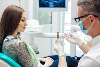 A dentist showing a dental implant to his patient