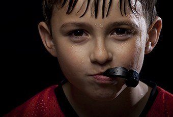 Young boy holding sportguard in mouth