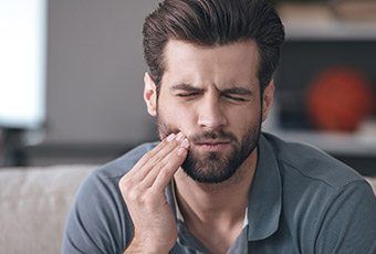 Man holding cheek in pain