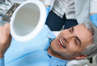 Man smiling at reflection in handheld mirror