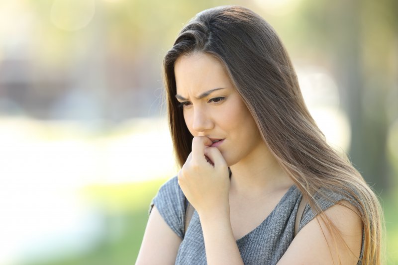 a young woman outside looking worried and biting her nails