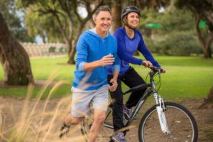 Older couple exercising outside with implant dentures in Ripon