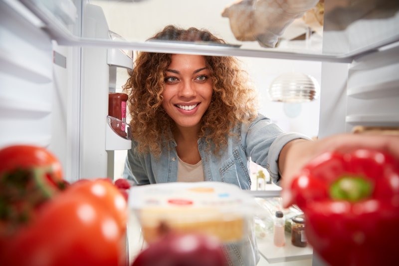 a woman with veneers checking her refrigerator for food