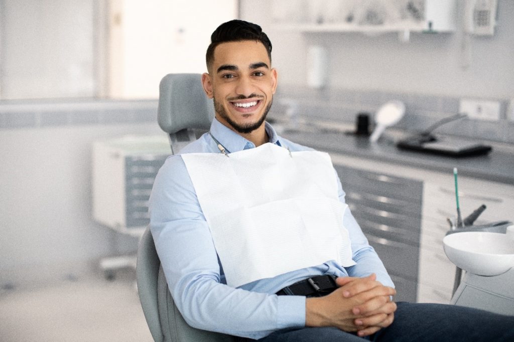 Man smiling while sitting in treatment chair at dentist's office